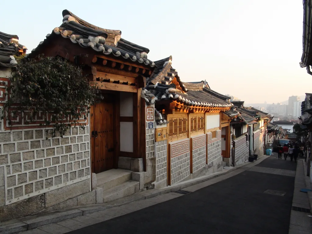 Tiled hanok roofs in Bukchon, with the modern city rising beyond them.
