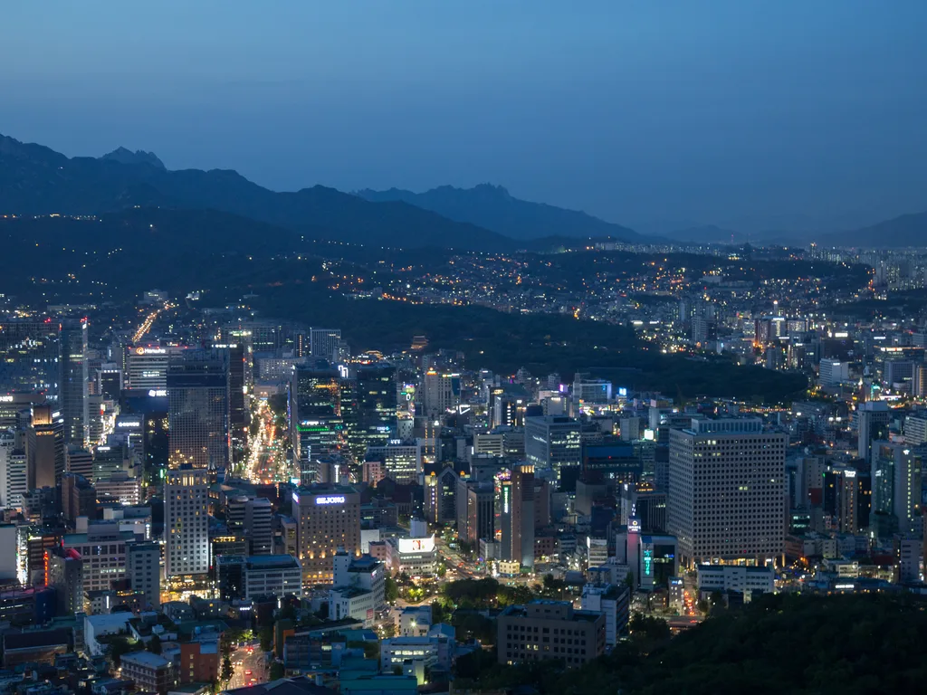 Seoul at dusk, the city filling the basin below the ridgeline of its mountains.