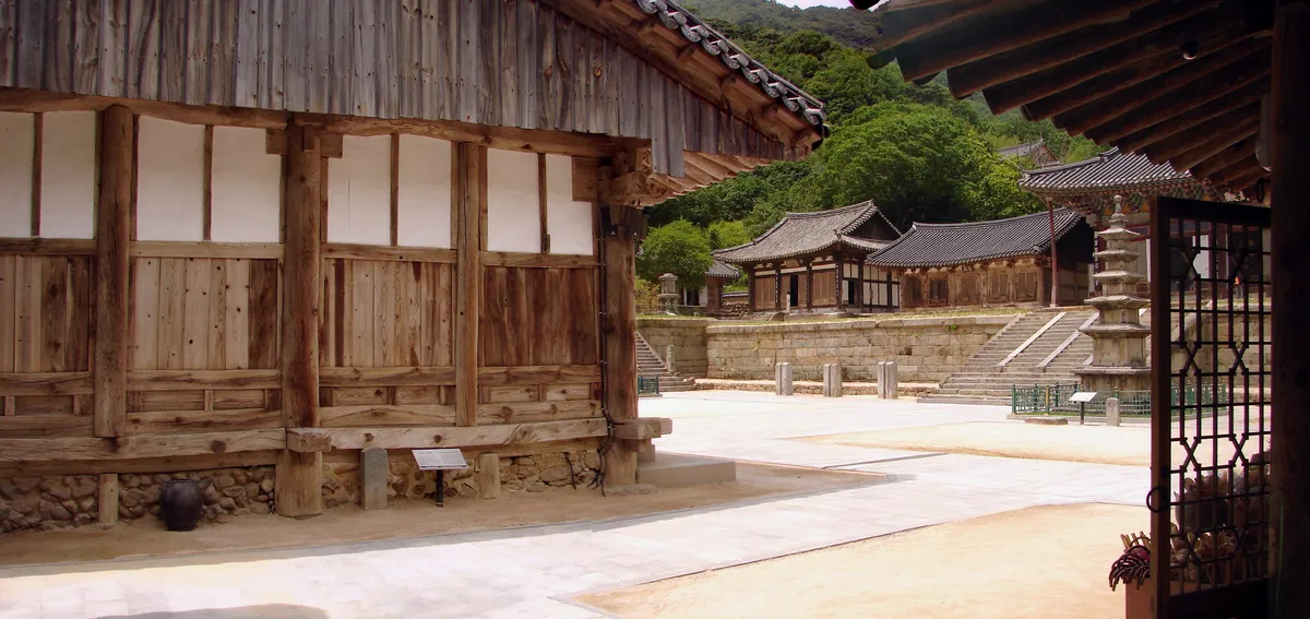 The two-storey Gakhwangjeon at Hwaeomsa, seven bays wide beneath the wooded slope of Jirisan.