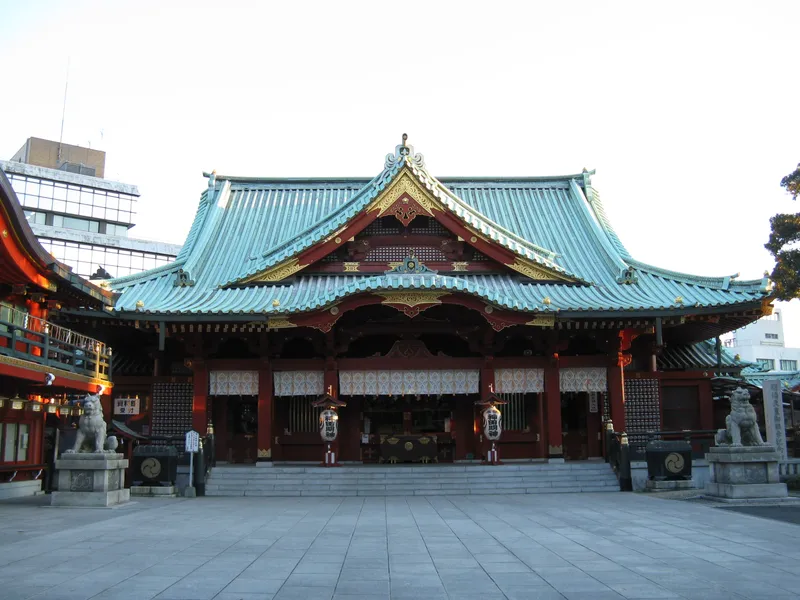 The vermilion main hall of Kanda Myojin, its wide roof rising above the courtyard