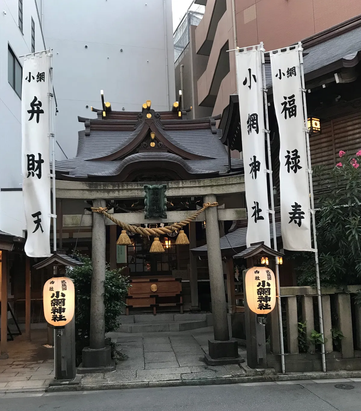 The small timber hall of Koami Shrine, closely surrounded by office buildings