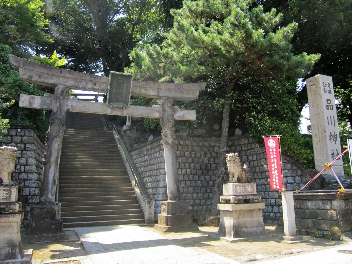 The torii of Shinagawa Shrine at the foot of its steps, carved with dragons