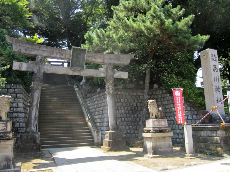 The torii of Shinagawa Shrine at the foot of its steps, carved with dragons