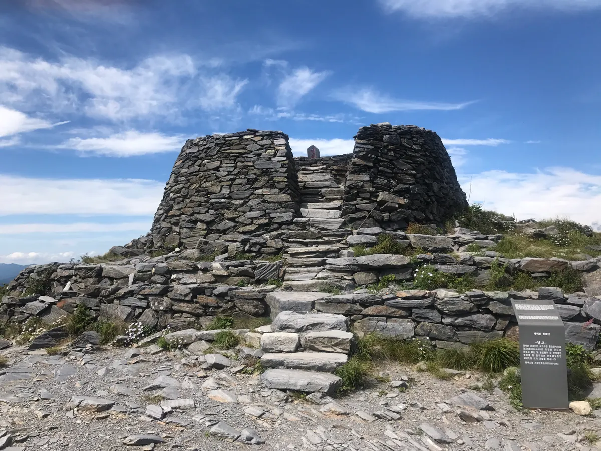 The stacked-stone heaven-rite altar on the summit of Taebaeksan, open sky above the ridge behind it.