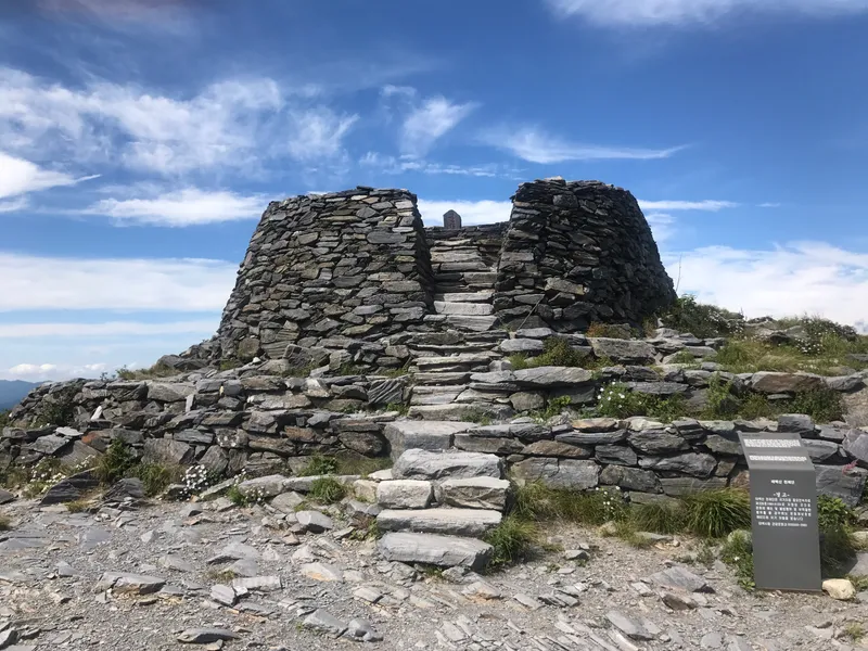 The stacked-stone heaven-rite altar on the summit of Taebaeksan, open sky above the ridge behind it.